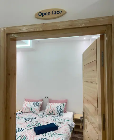 The pine door of the ‘Open face’ room at Line Up, its wooden name plaque above, and a double bed inside
