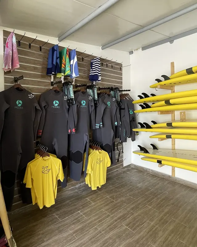 Inside the Line Up shop: wetsuits on a rail, yellow Line Up T-shirts and a rack of yellow boards
